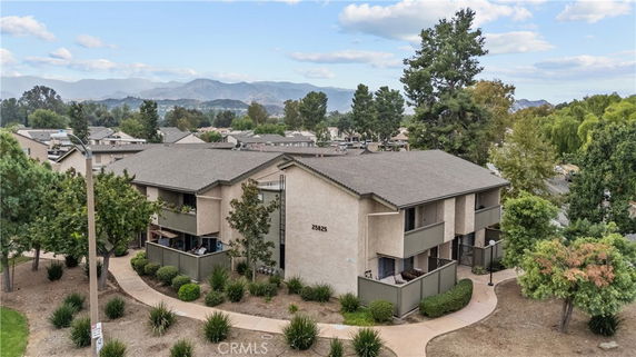 Front view of a two-story apartment building with balconies and surrounding landscape.
