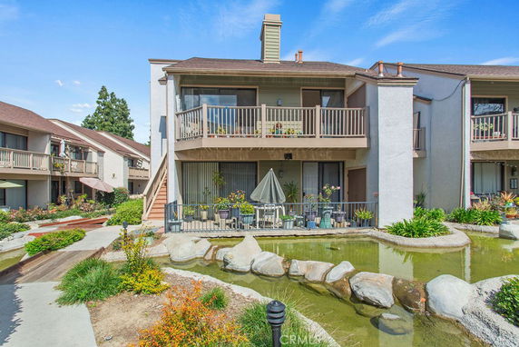Front view of a two-story building with balconies and a pond.