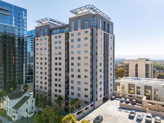 Front view of a high-rise building with multiple windows and a parking area.