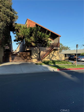 Front view of a two-story building with an exterior staircase and gated entrance.