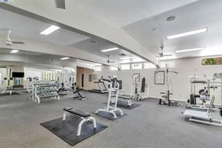 Indoor gym area with various exercise equipment and mirrors.