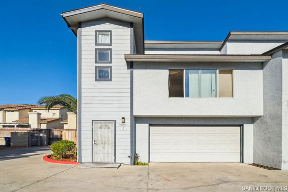 Front view of a two-story house with a garage and vertical windows.