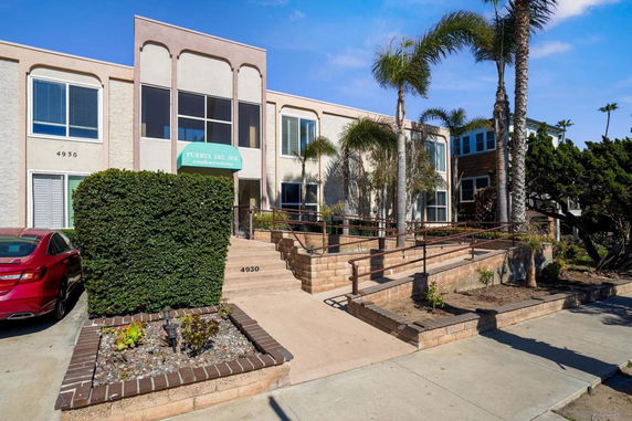 Front view of a two-story condominium with a ramp and steps leading to the entrance.