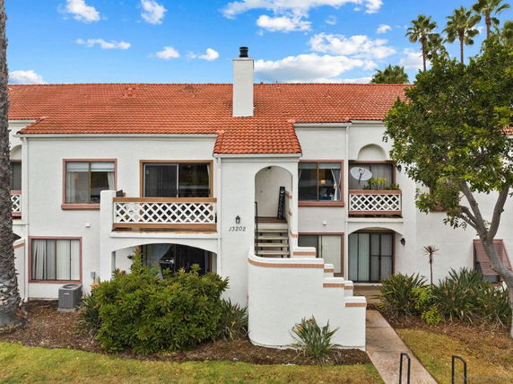 Front view of a two-story house with red tile roof and balconies.