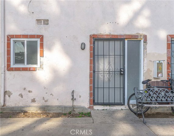 Front view of a building with a metal door and small window with red brick trim.