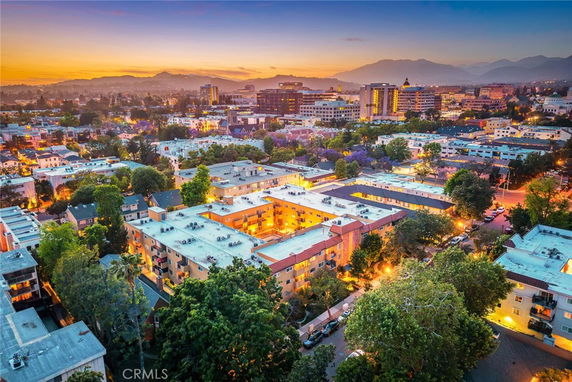 Panoramic view of a cityscape with multiple buildings and a scenic sunset.