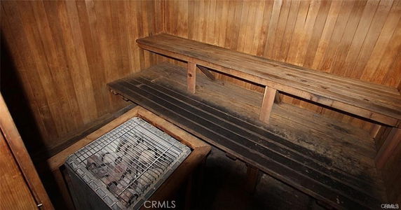 Interior of a wood-paneled sauna room with a heater and wooden benches.