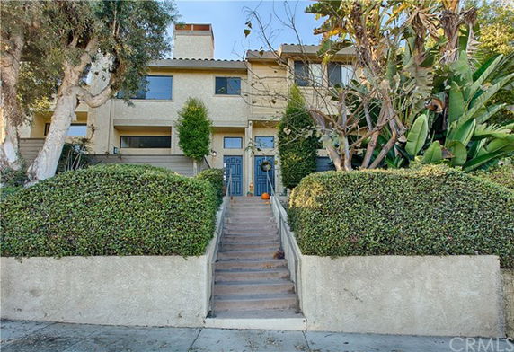 Front view of a two-story house with stairs leading to the entrance.