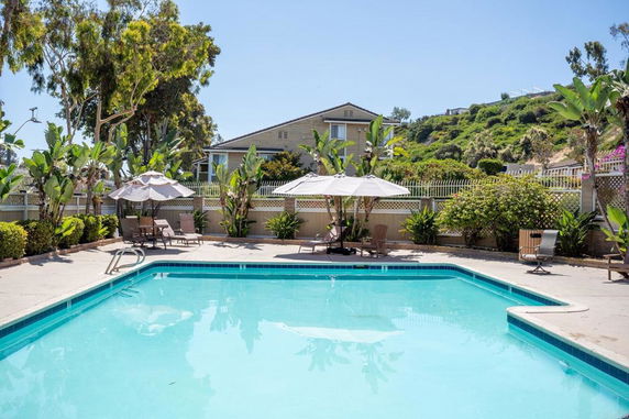 Outdoor swimming pool area with a house in the background.