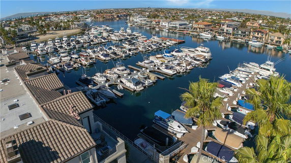 Panoramic view of a marina with numerous boats docked and houses in the background.