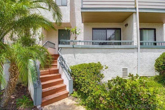 Front view of a multi-story house entrance with stairs and balcony.