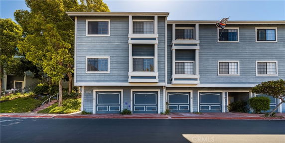 Front view of a multi-story building with garages at the ground level and windows on the upper floors.