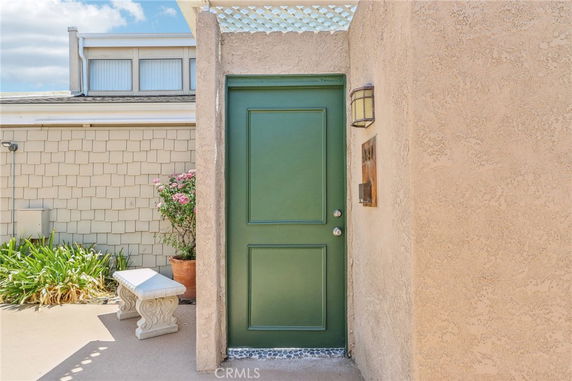 Front view of a building entrance with a green door and beige stucco walls.