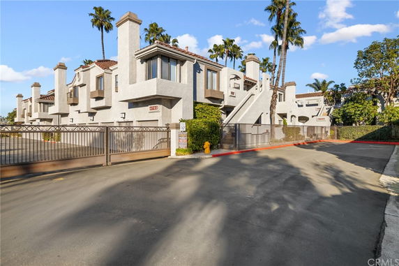 Front view of a multi-story residential building with chimney features and a gated entrance.