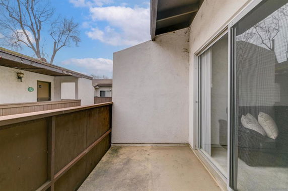 View from a small balcony area with sliding glass doors and adjacent building visible.