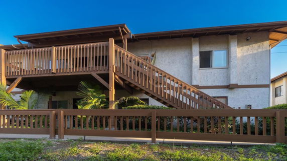 Front view of a two-story house with wooden railings and stairs.