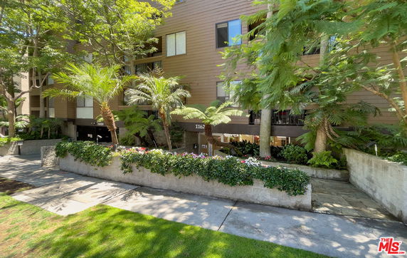 Front view of a multi-story residential building with surrounding greenery.