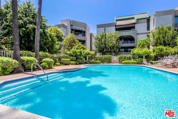 Outdoor swimming pool in front of a multi-story residential building.
