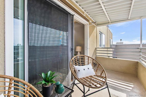 Balcony with two chairs and a side table, partially covered by a roof.