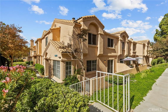 Front view of a multi-story townhouse with a tan exterior and a small front patio.