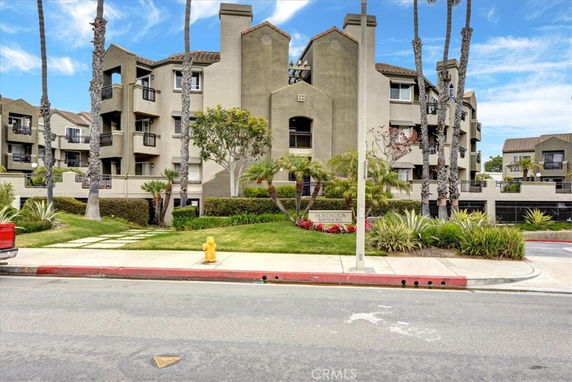 Front view of a multi-story residential building with balconies and a landscaped garden.