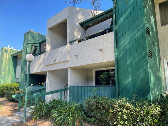 Front view of a multi-story building with balconies and green trim.
