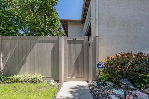 Front view of a house entrance with a wooden gate and stucco wall.