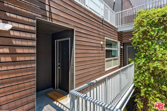 Exterior view of a modern building entrance with wood paneling and metal railing.