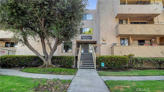 Front view of a multi-story building with balconies and an entrance stairway.