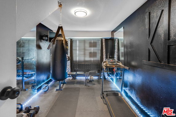Indoor gym area with exercise equipment including a punching bag, treadmill, and weights.