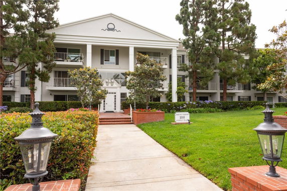 Front view of a three-story building with balconies and a gabled roof.