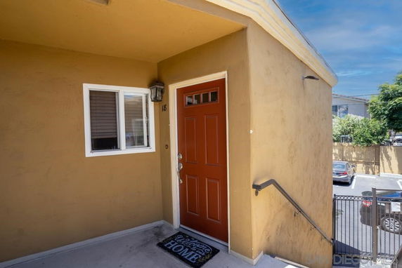 Entrance view of a building with a red door and nearby parking area.