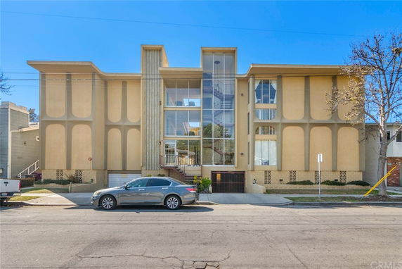 Front view of a multi-story building with large glass windows and beige facade.