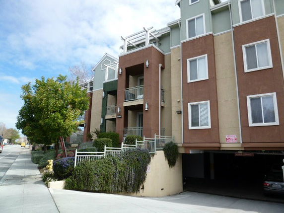 Front view of a multi-story residential building with balconies and a parking area entrance at the bottom.