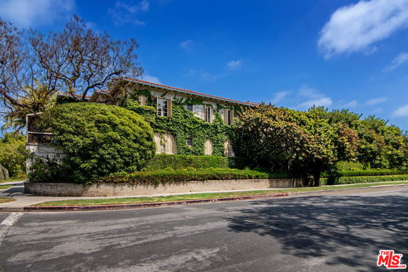 Front view of a two-story house with ivy-covered walls and a sloped roof.