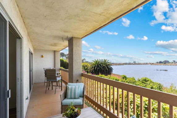 Outdoor balcony overlooking a scenic water body with a seating area.