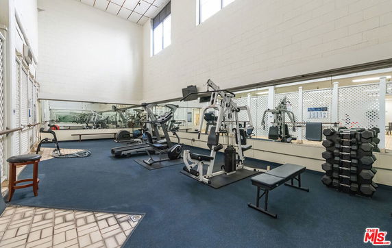 Indoor gym area with fitness equipment and mirrors on the walls.