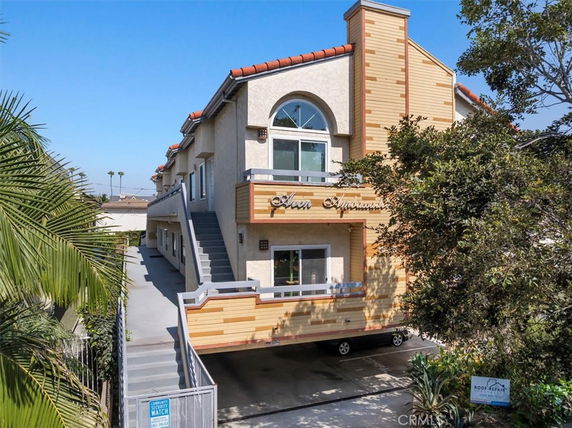 Front view of a multi-story residential building with outdoor stairs and a gated entrance.