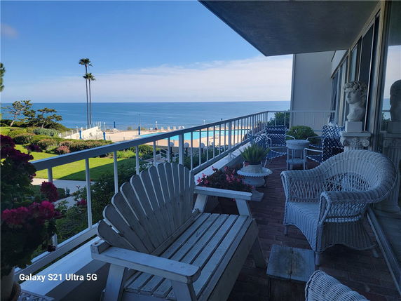 Balcony view overlooking the ocean with outdoor seating and a railing.