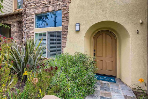 Front view of a house with a stone facade and arched entryway.