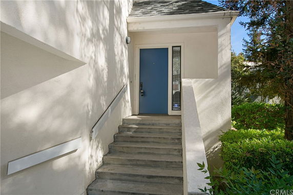 Front view of a house with a staircase leading up to a blue door entrance.