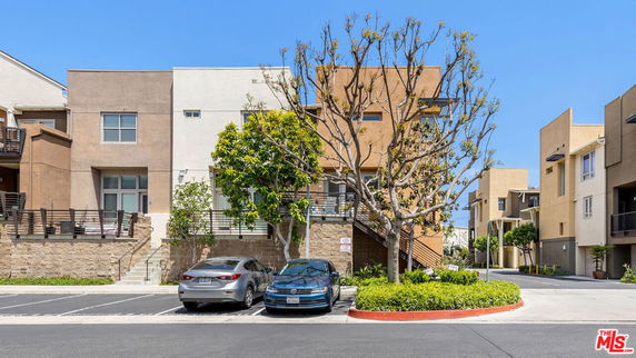 Front view of a modern multi-story building with adjacent parking area.