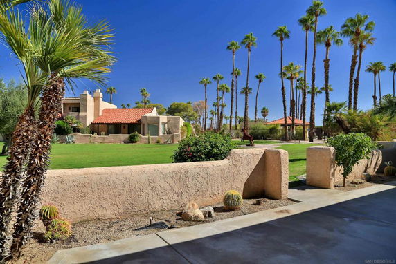 View of a landscaped area with a house and palm trees.