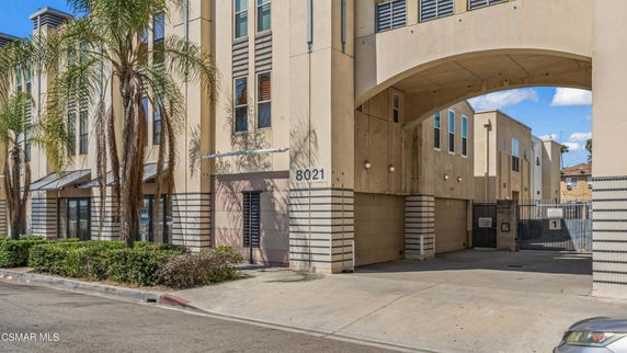 Front view of a multi-story building with an arched entrance and palm trees.