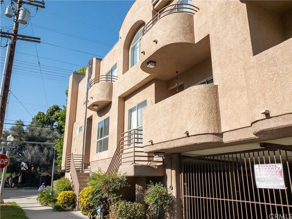 Front view of a multi-story building with balconies and a gated entrance.