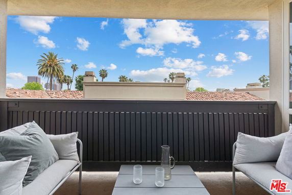 Panoramic view from a balcony showing rooftops and distant city skyline.