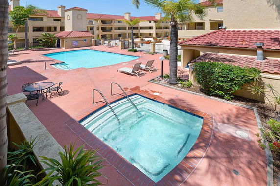 Outdoor swimming pool area with adjacent hot tub and sun loungers.