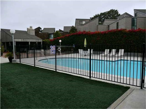 Outdoor swimming pool with a surrounding fence and nearby residential buildings