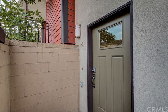 Front view of a house entrance with a light brown door and surrounding walls.
