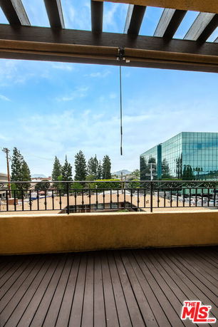 Panoramic view from a building with urban surroundings, including a modern glass building and trees.